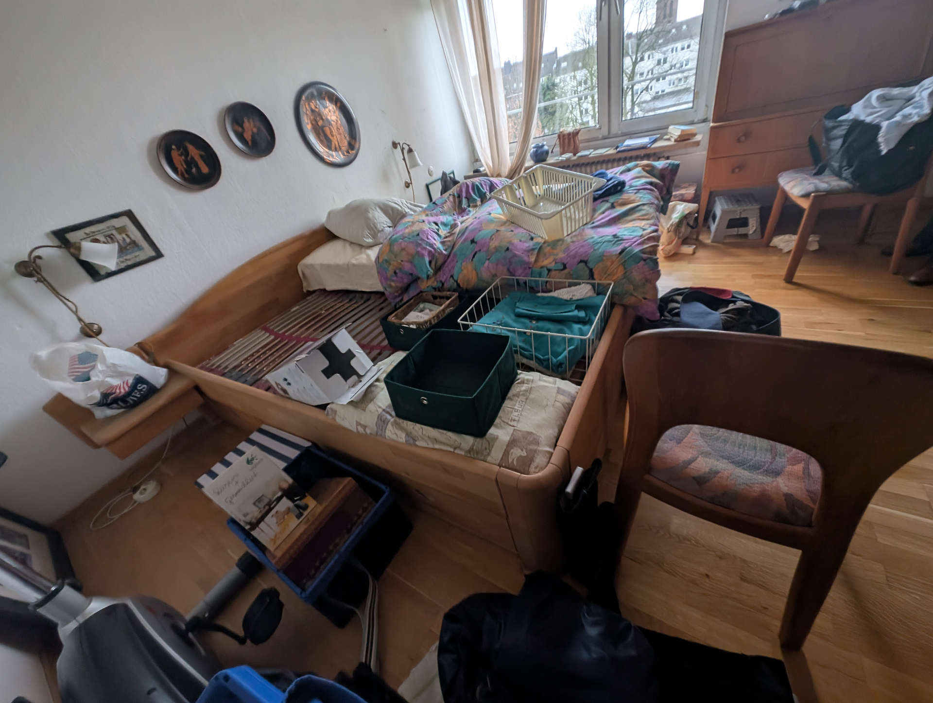 Unordentliches Schlafzimmer: Bett mit Gegenständen, Stühlen, Beistelltischen und Wanddekorationen.