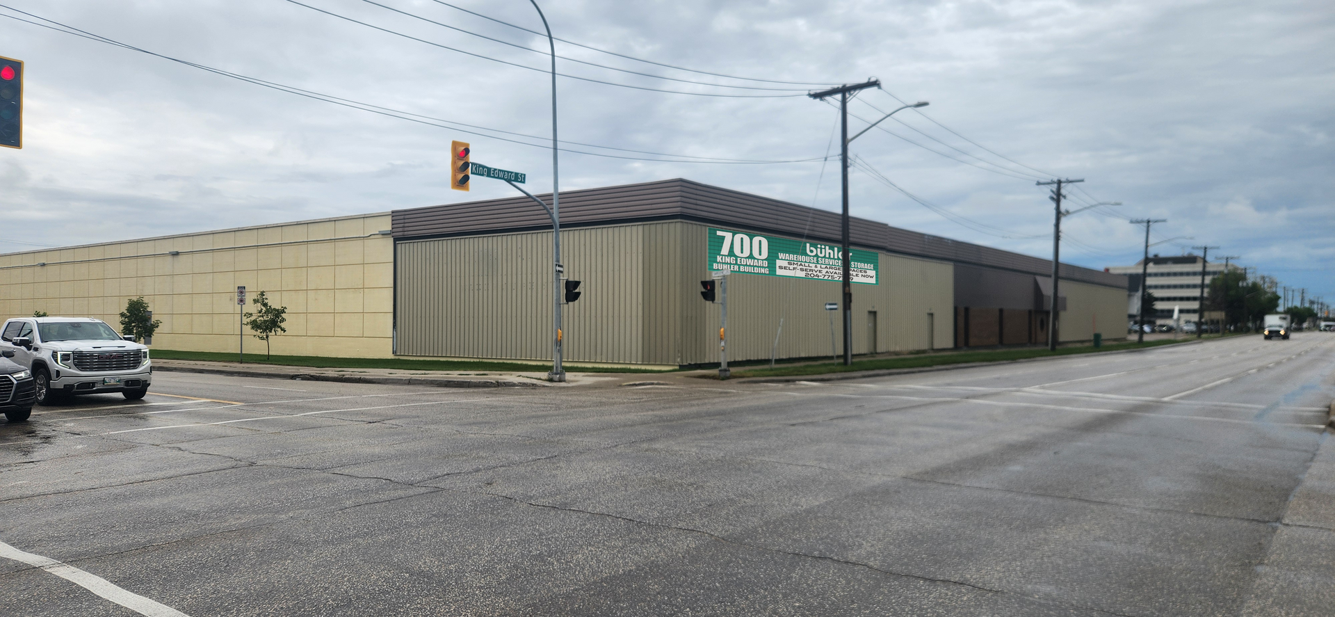 A large warehouse building is sitting on the corner of a street.