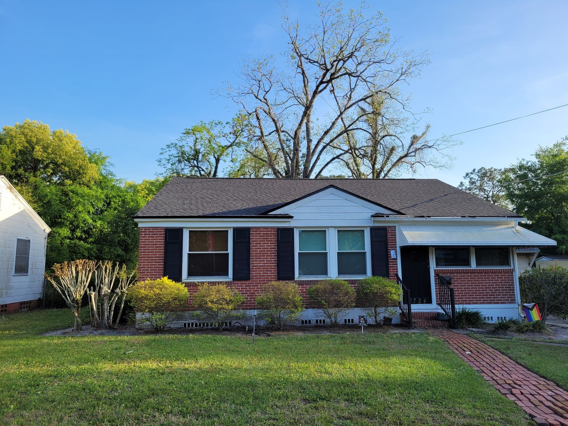 Brick bungalow house with a dark roof and green lawn.