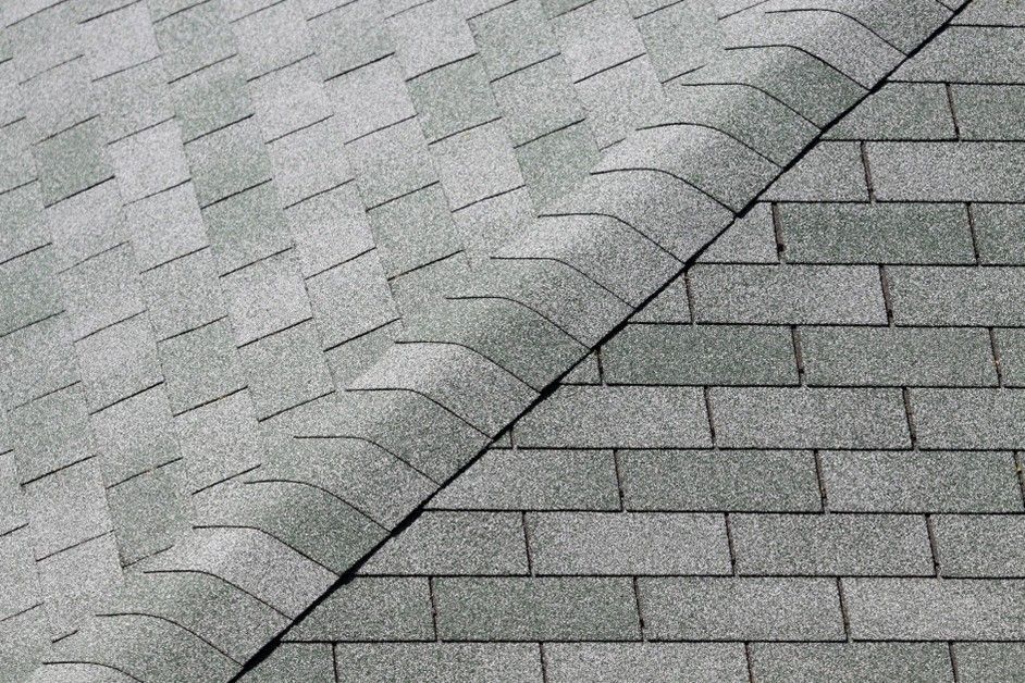 Roof close-up with gray and green diagonal shingles forming a textured overlapping pattern
