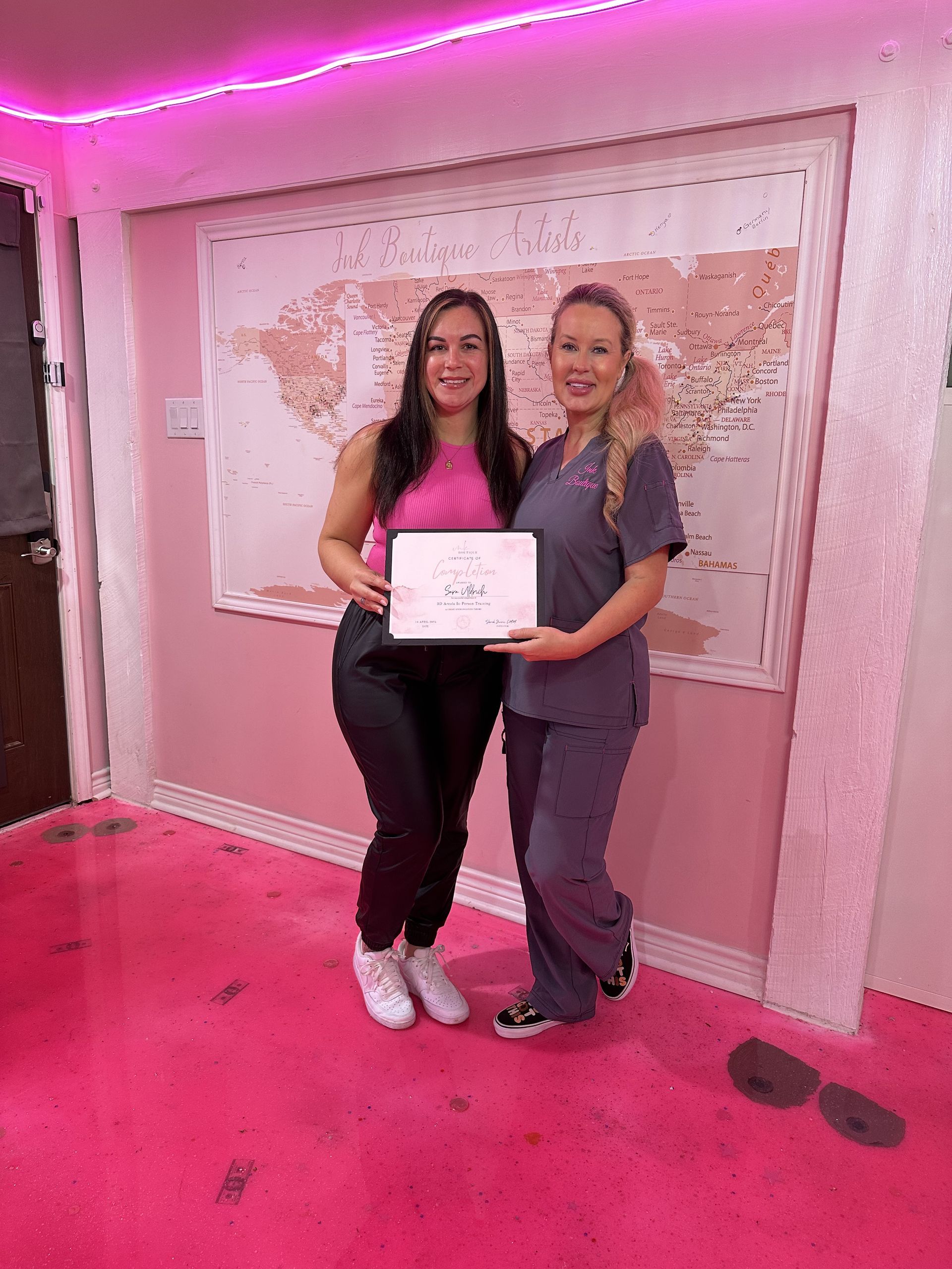 Two women are standing next to each other in a room holding a certificate.