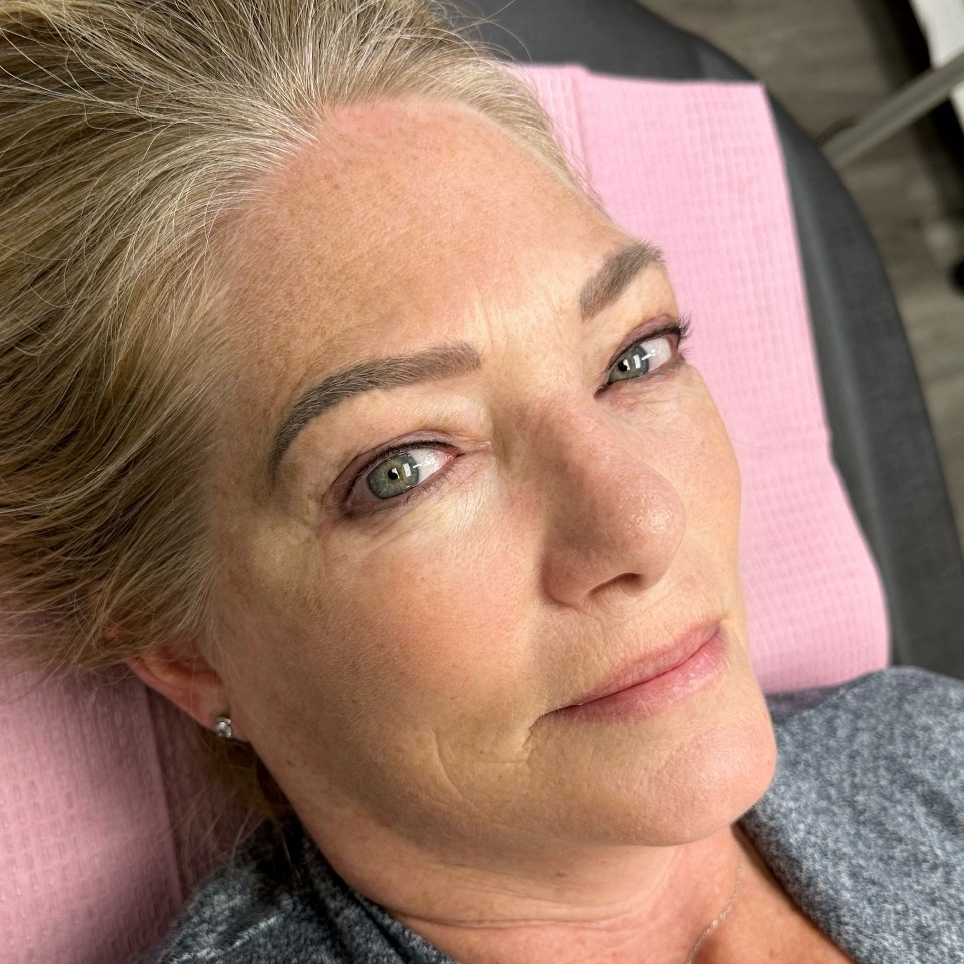 A close up of a woman 's face laying on a pink towel.