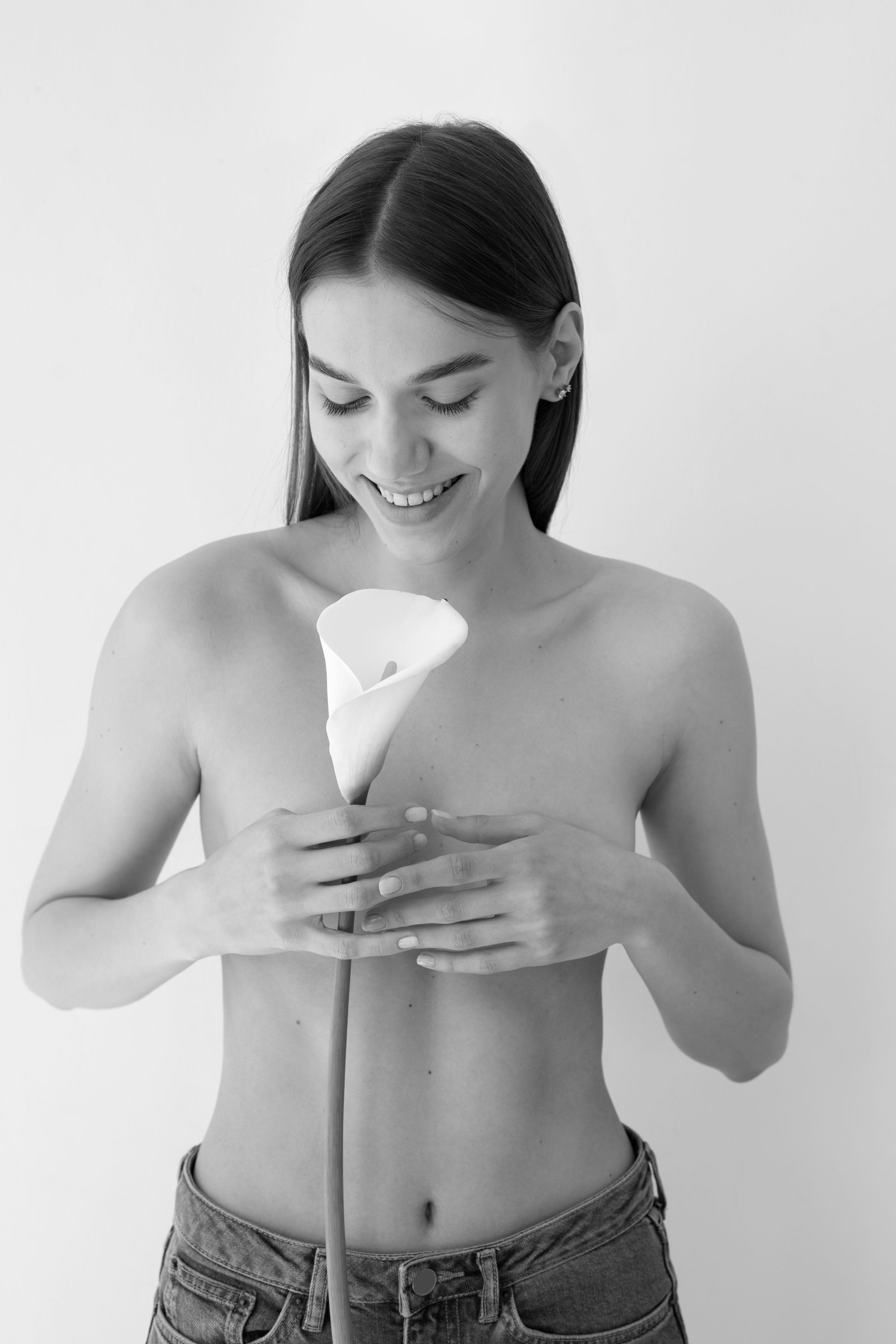 A black and white photo of a shirtless woman holding a flower.