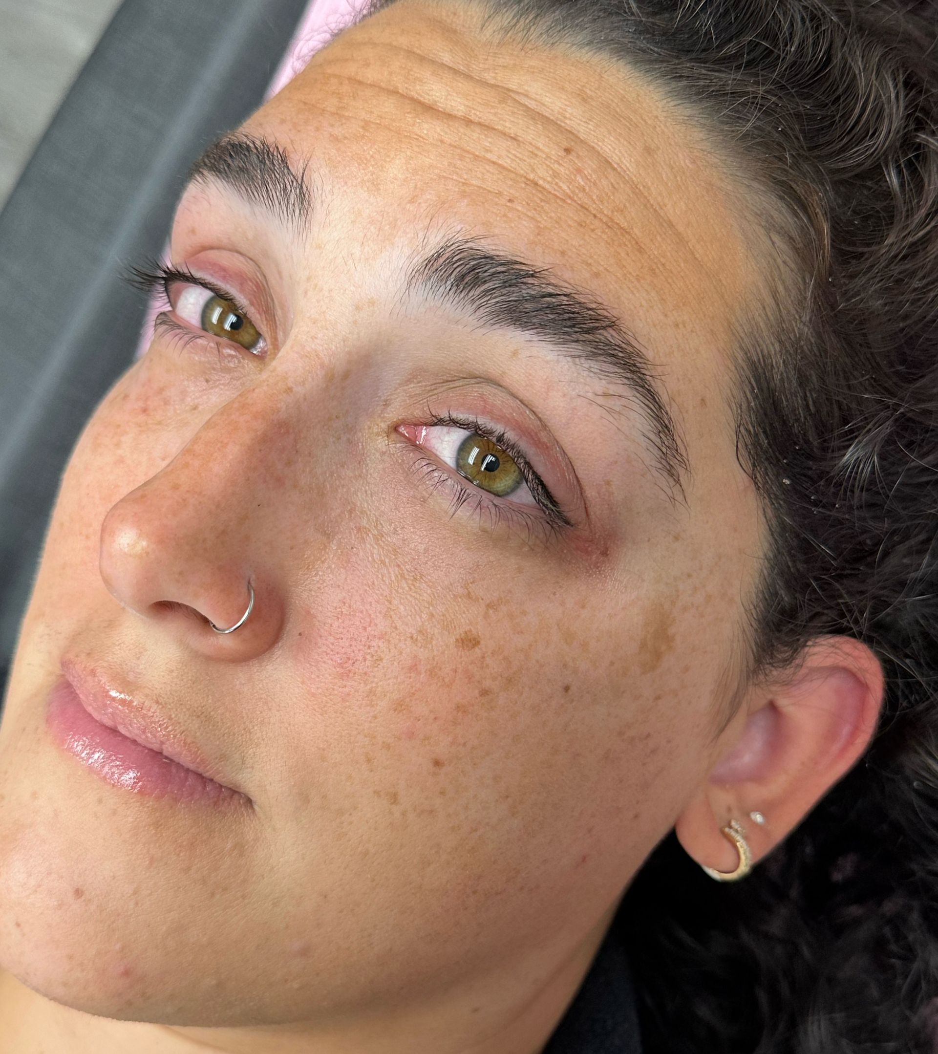 A close up of a woman 's face with a nose ring and earrings.
