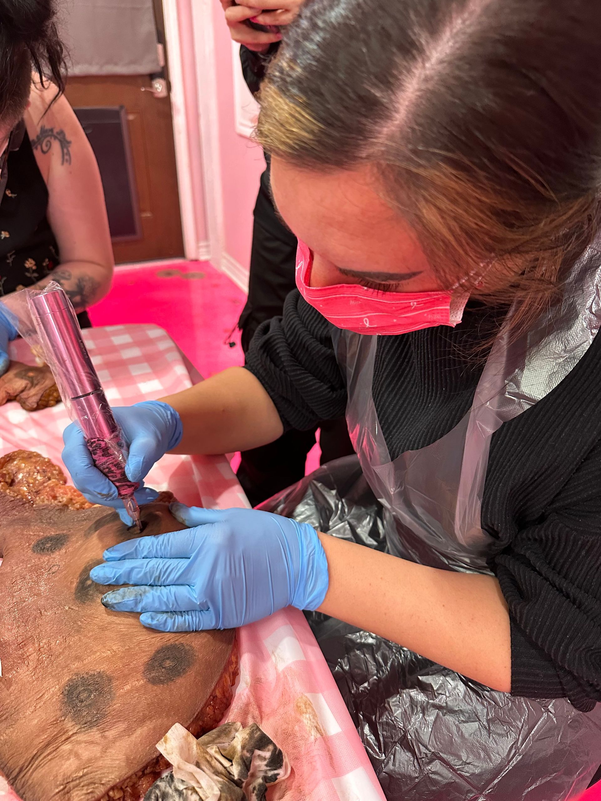A woman is getting a tattoo on a pig 's back.