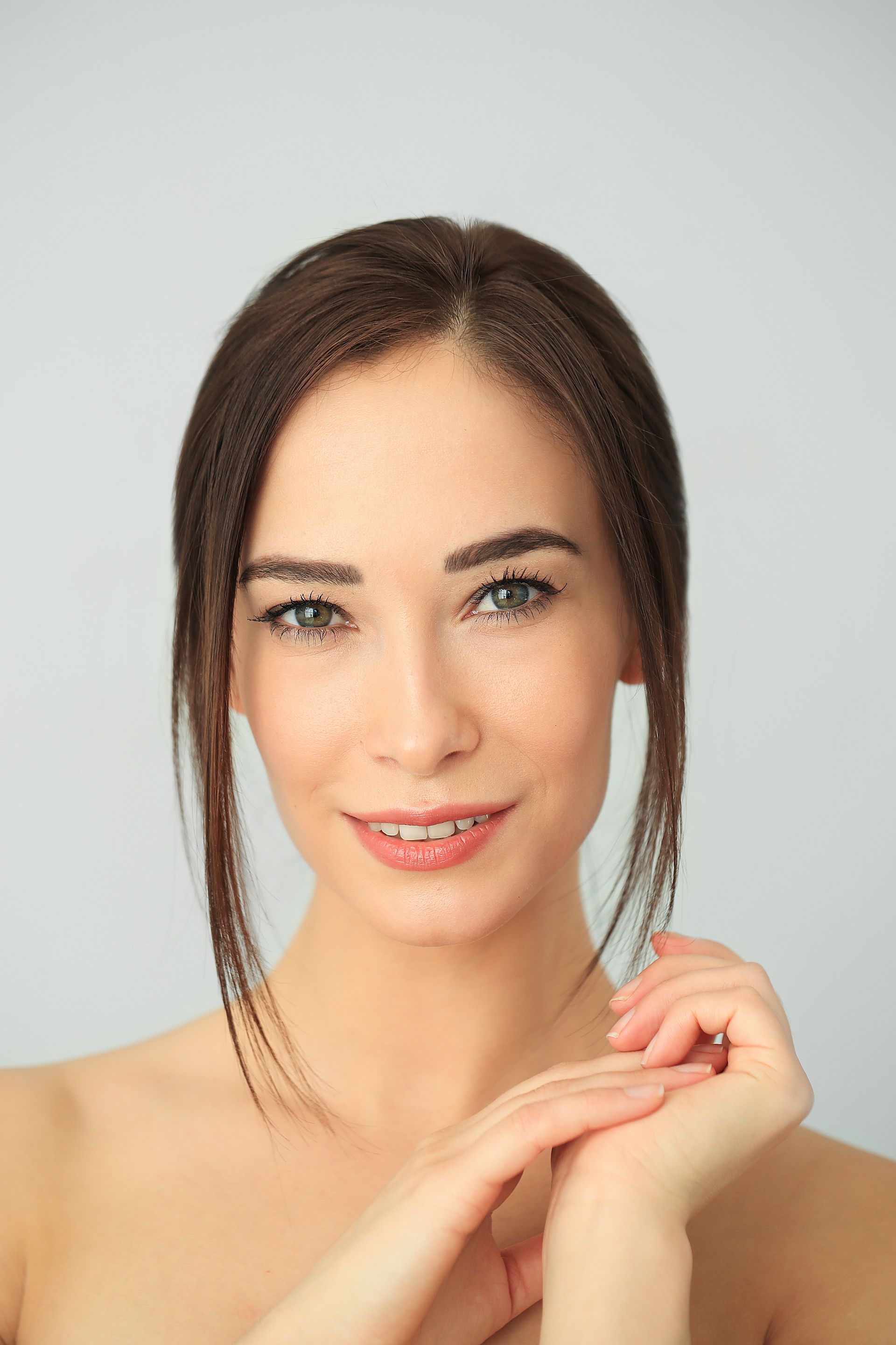 A close up of a woman 's face with her hands on her chin.