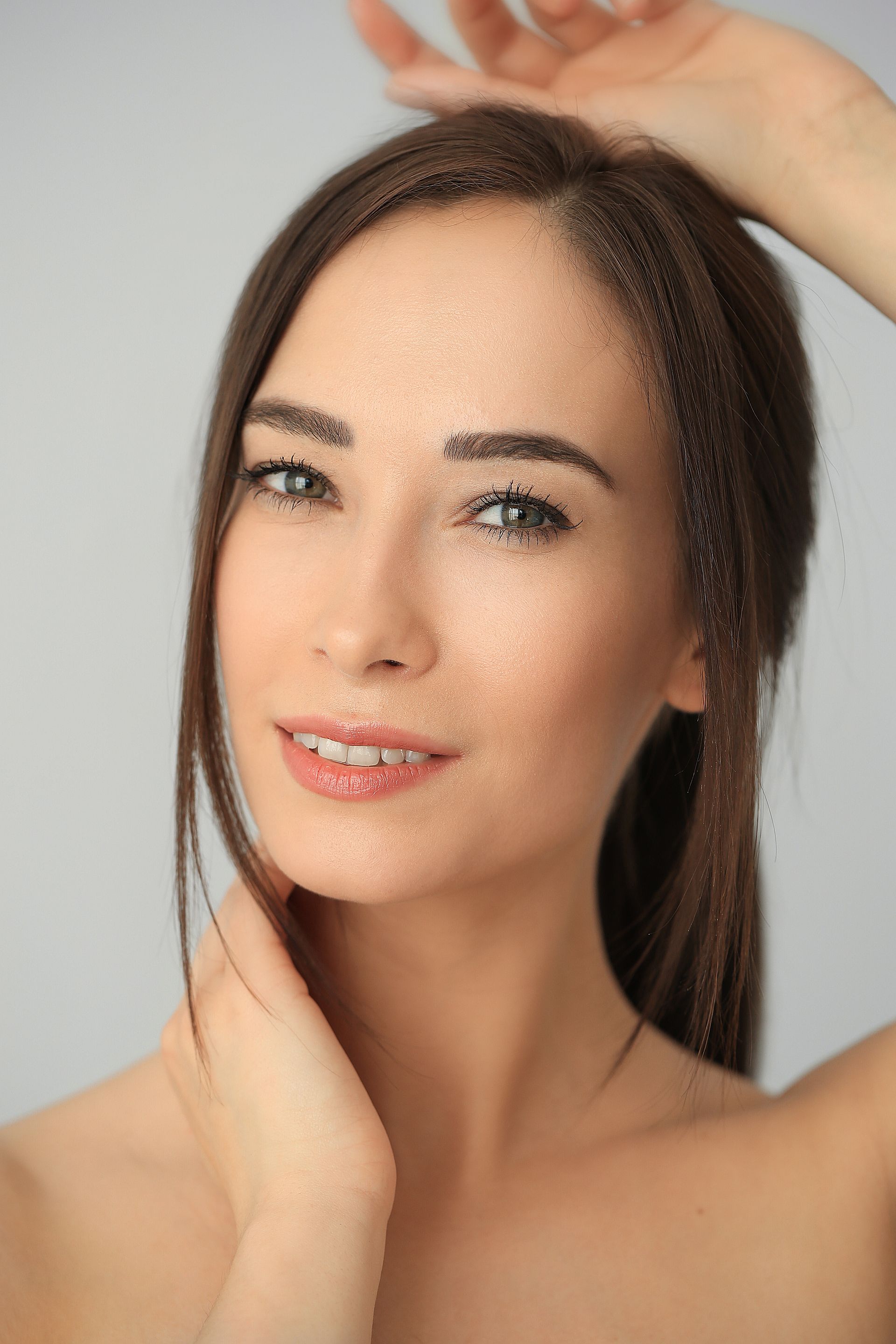 A close up of a woman 's face with her hand on her hair.