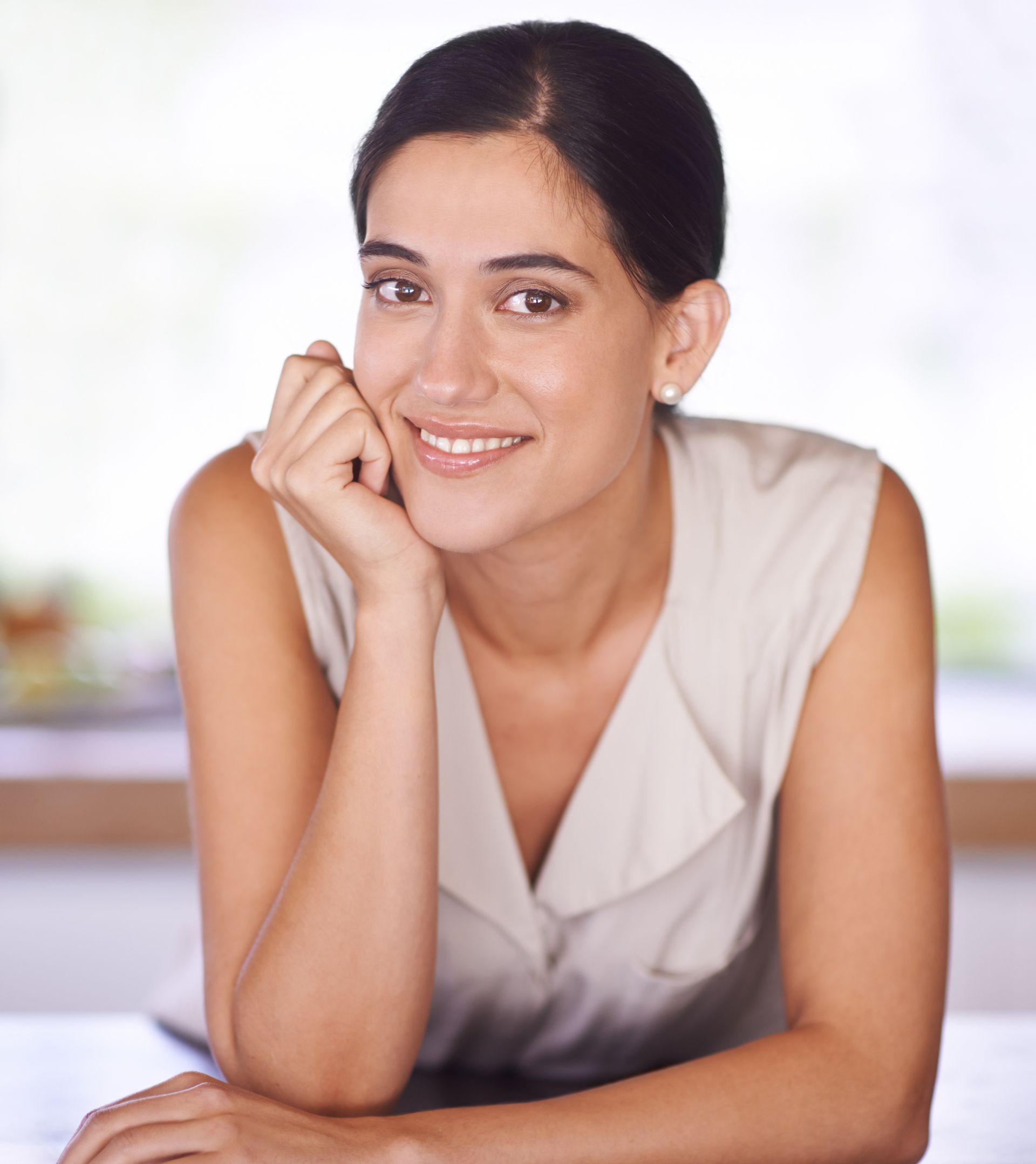 A woman is smiling with her hand on her chin