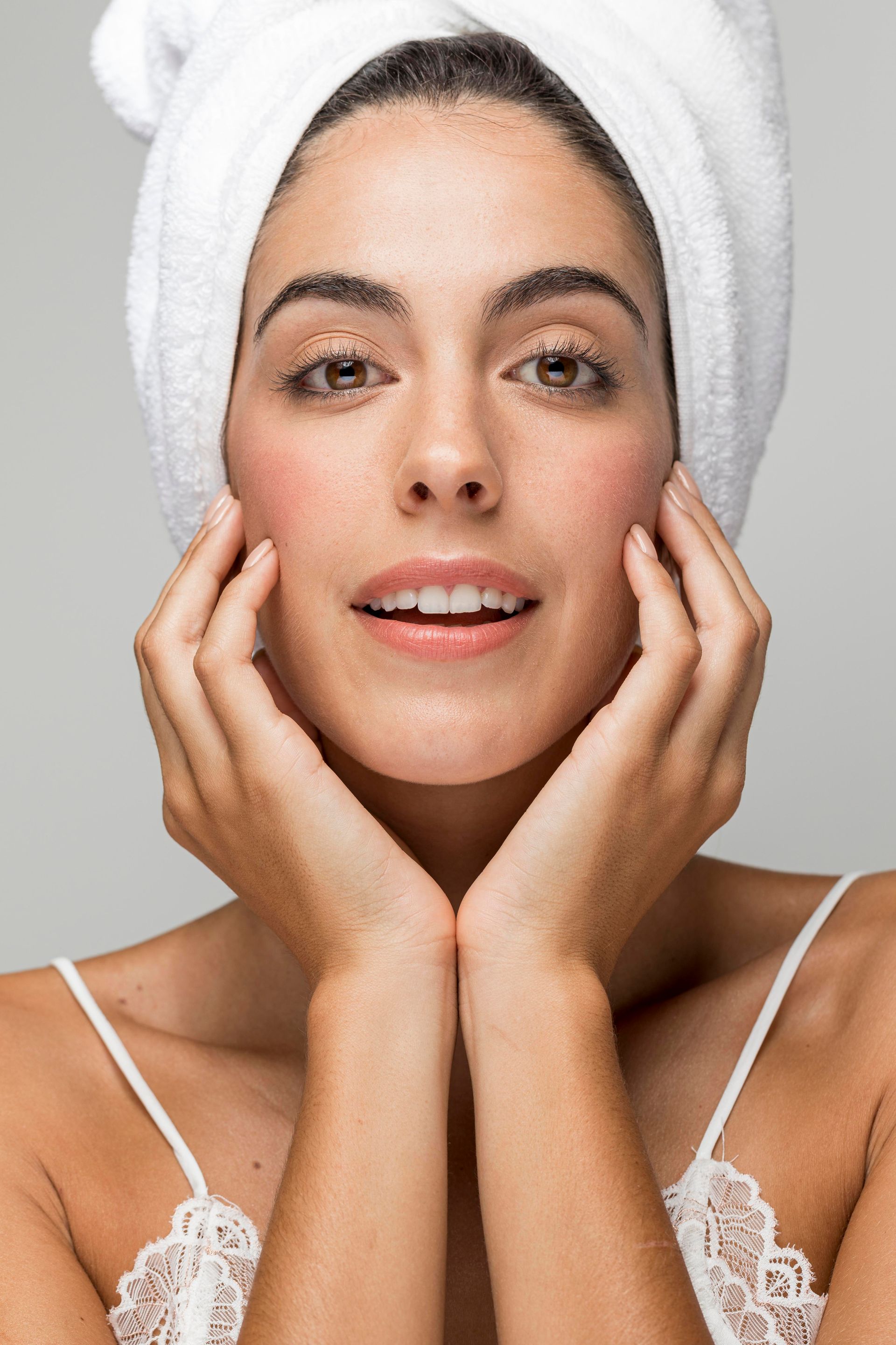 A woman with a towel wrapped around her head is smiling.