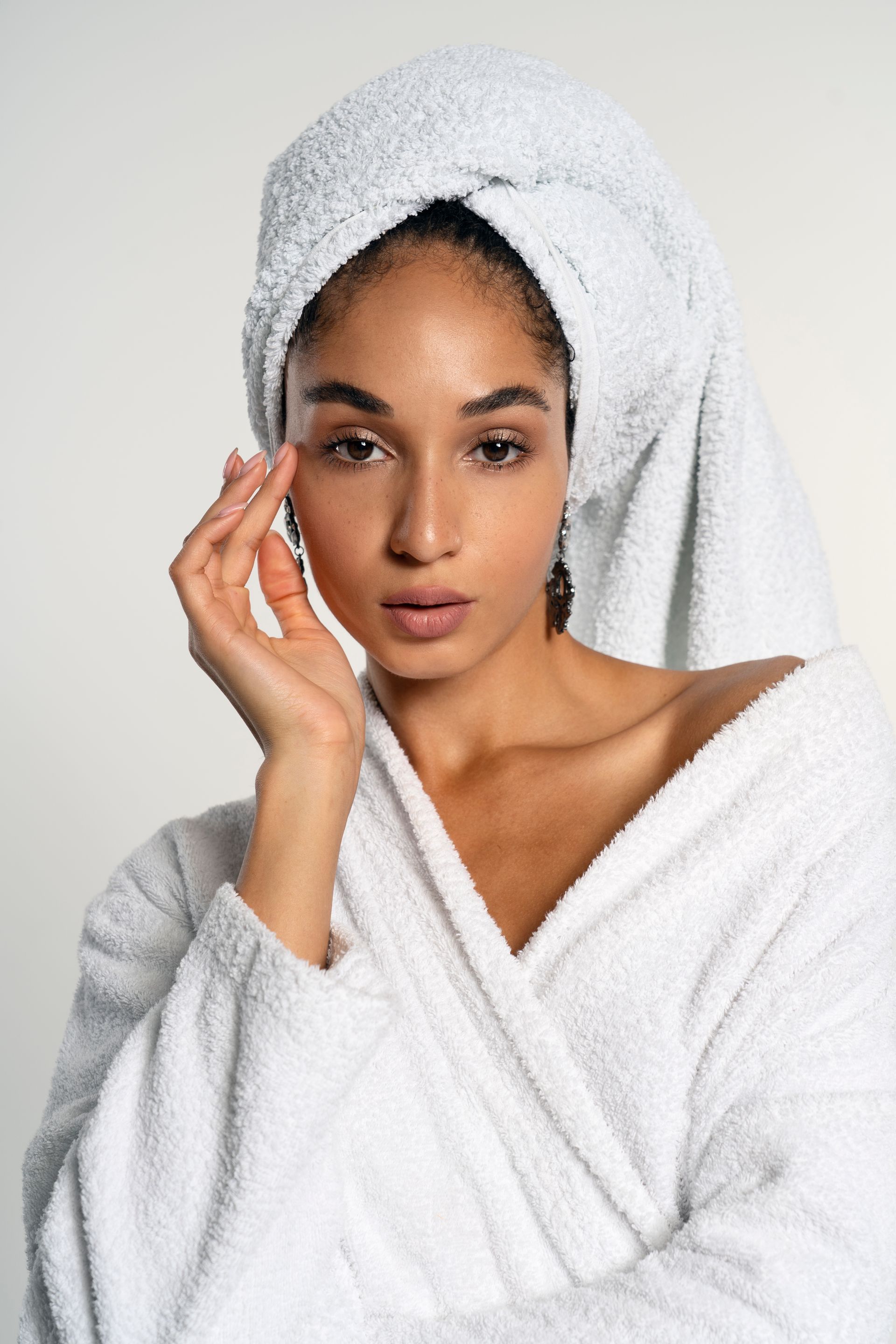 A woman in a white robe with a towel wrapped around her head.