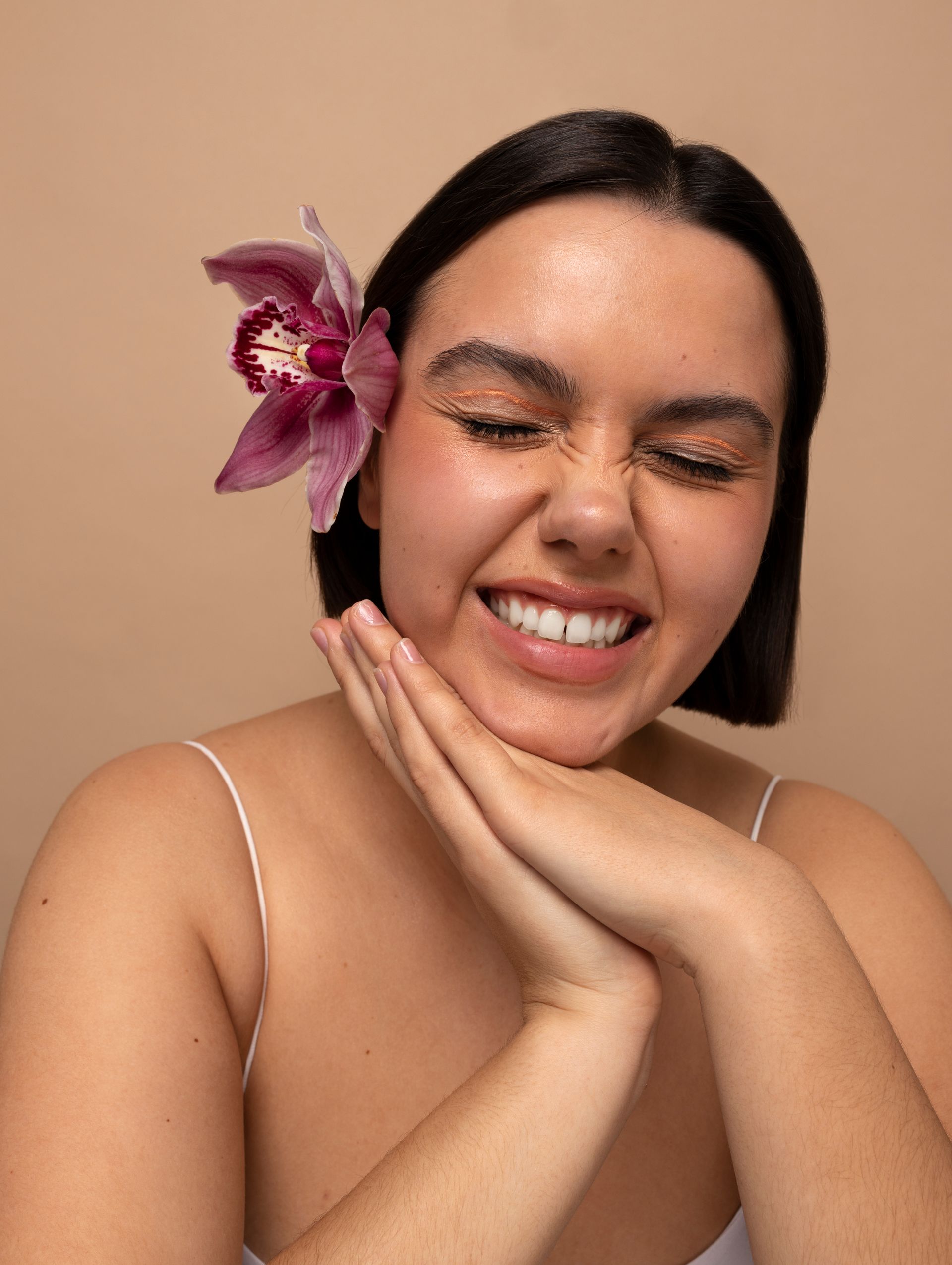 A woman with a flower in her hair is smiling.