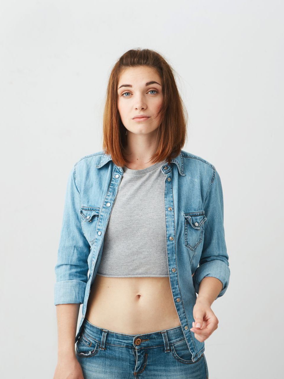 A woman is wearing a denim shirt and a crop top.