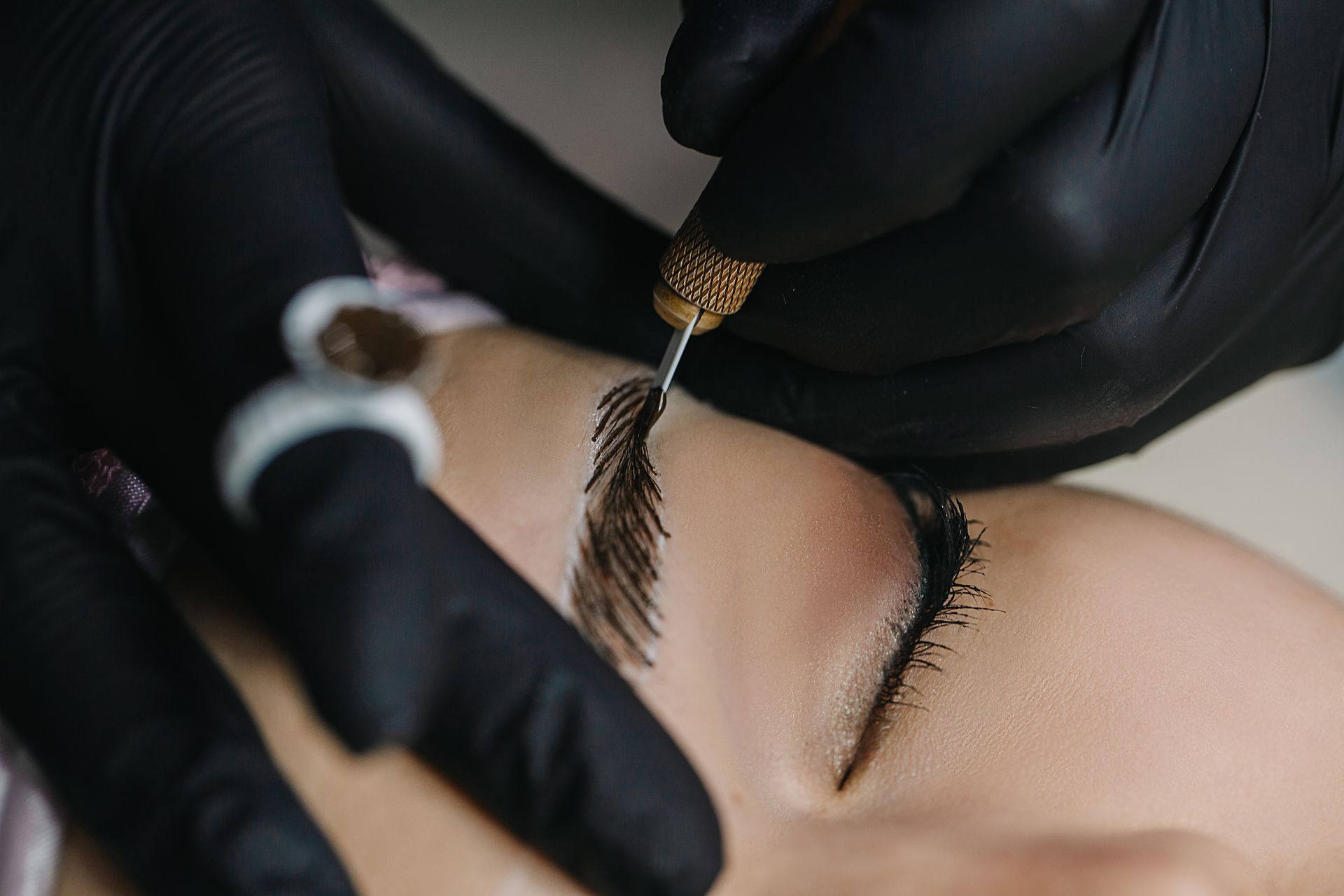 A woman is getting a permanent makeup tattoo on her eyebrows.