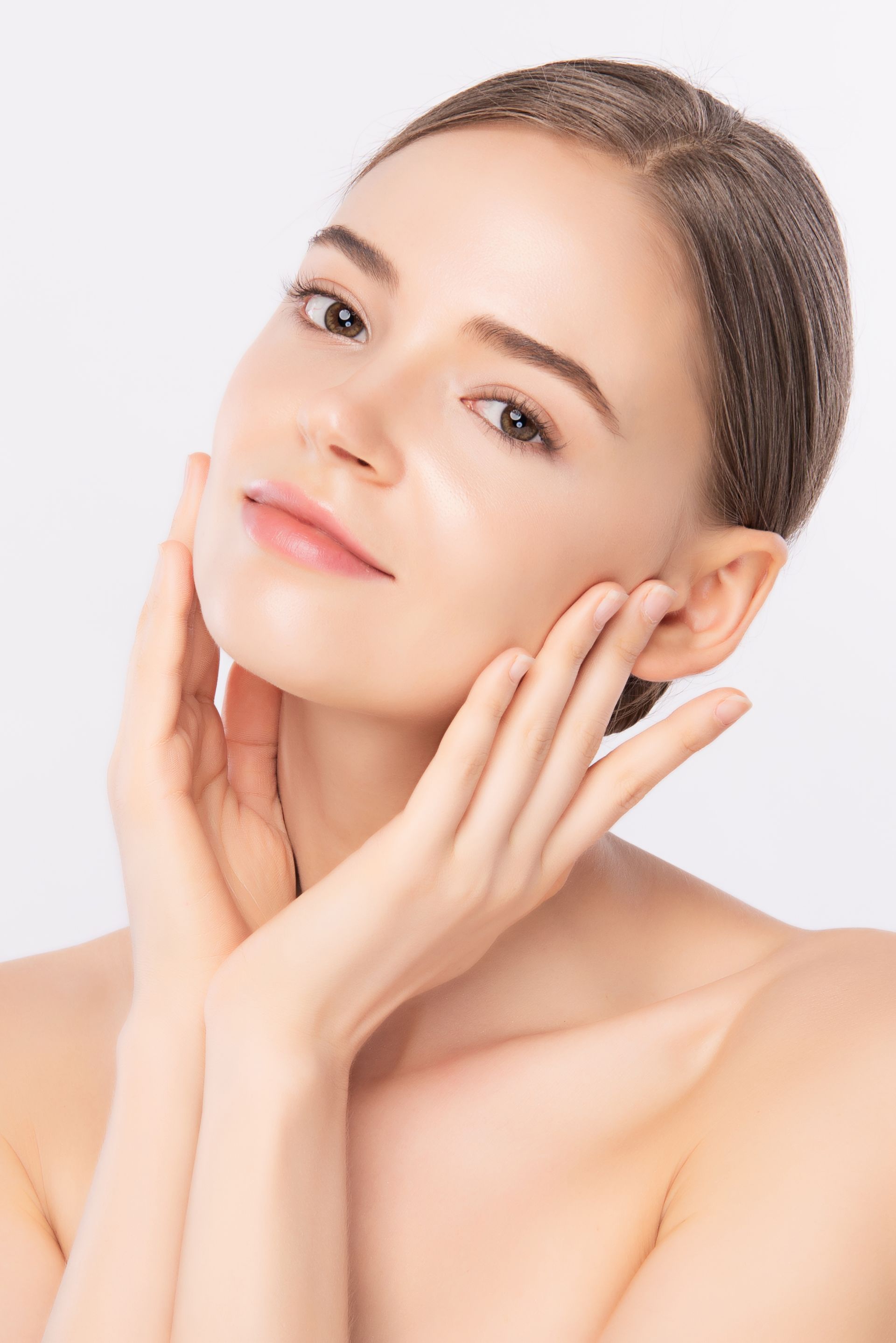 A woman is touching her face with her hands and smiling.