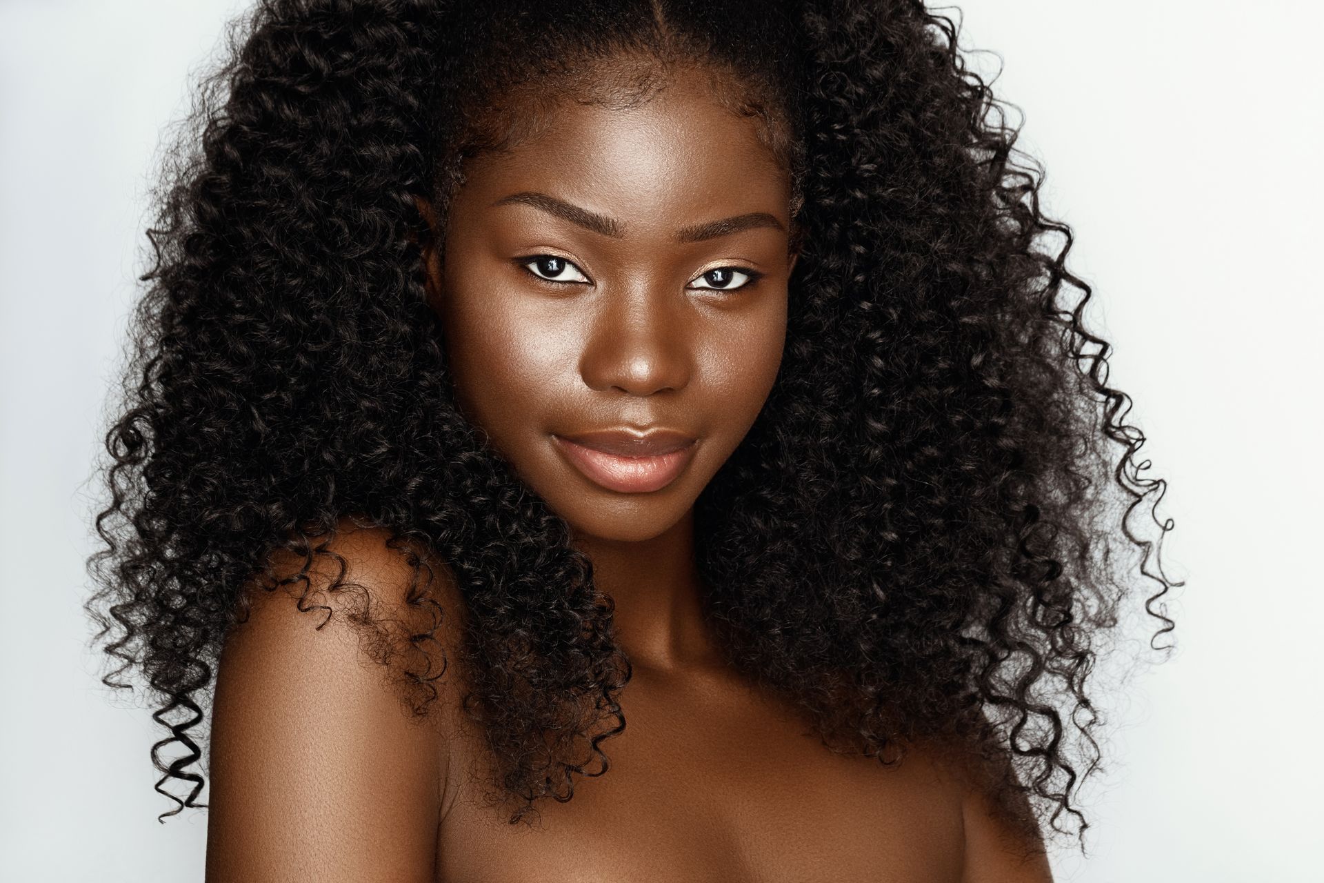 A woman with curly hair is smiling and looking at the camera.