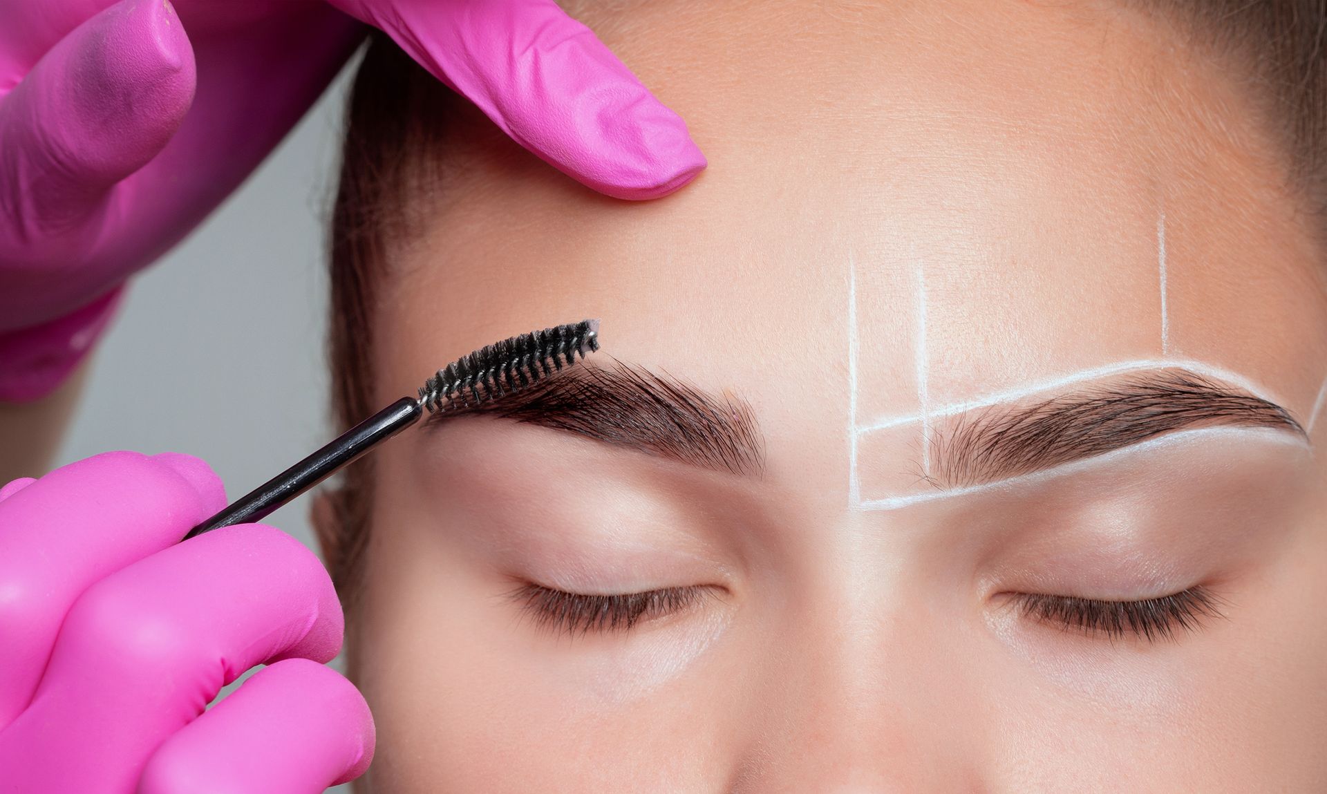 A woman is getting her eyebrows painted by a makeup artist.