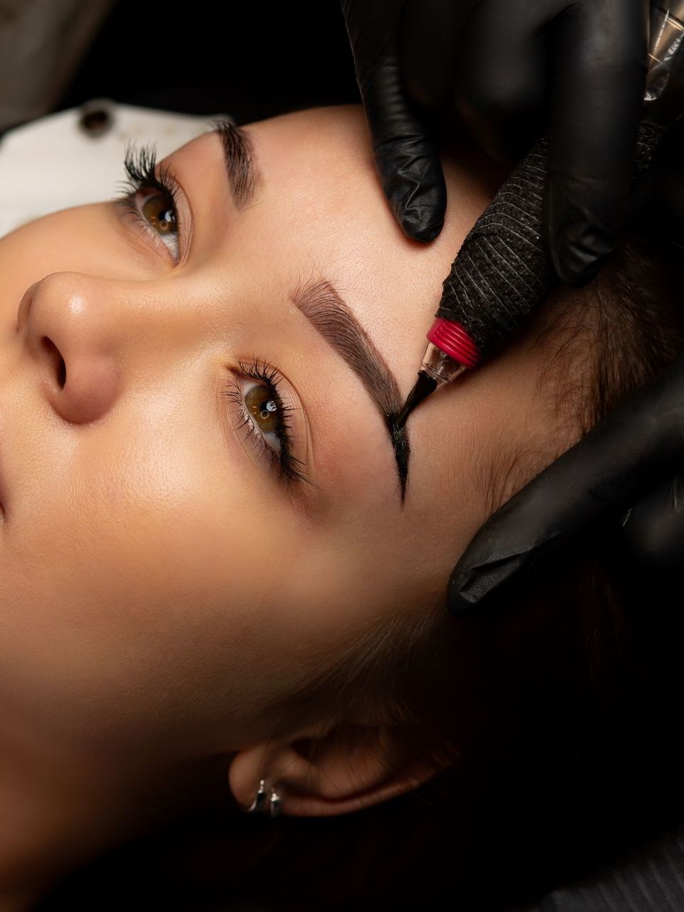 A woman is getting a tattoo on her eyebrows.