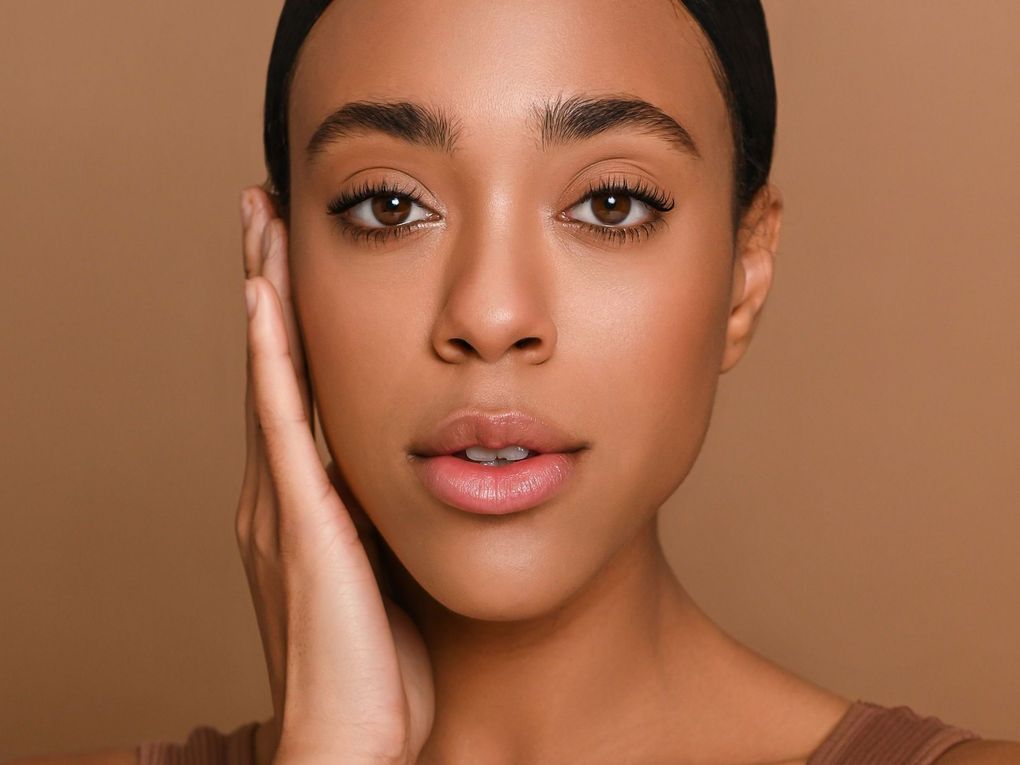 A close up of a woman 's face with her hand on her face.