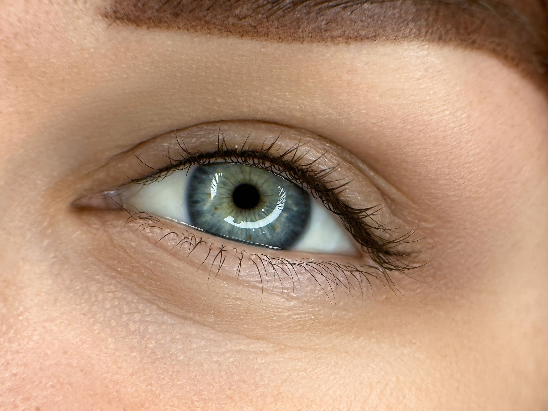 A close up of a woman 's blue eye with makeup on.