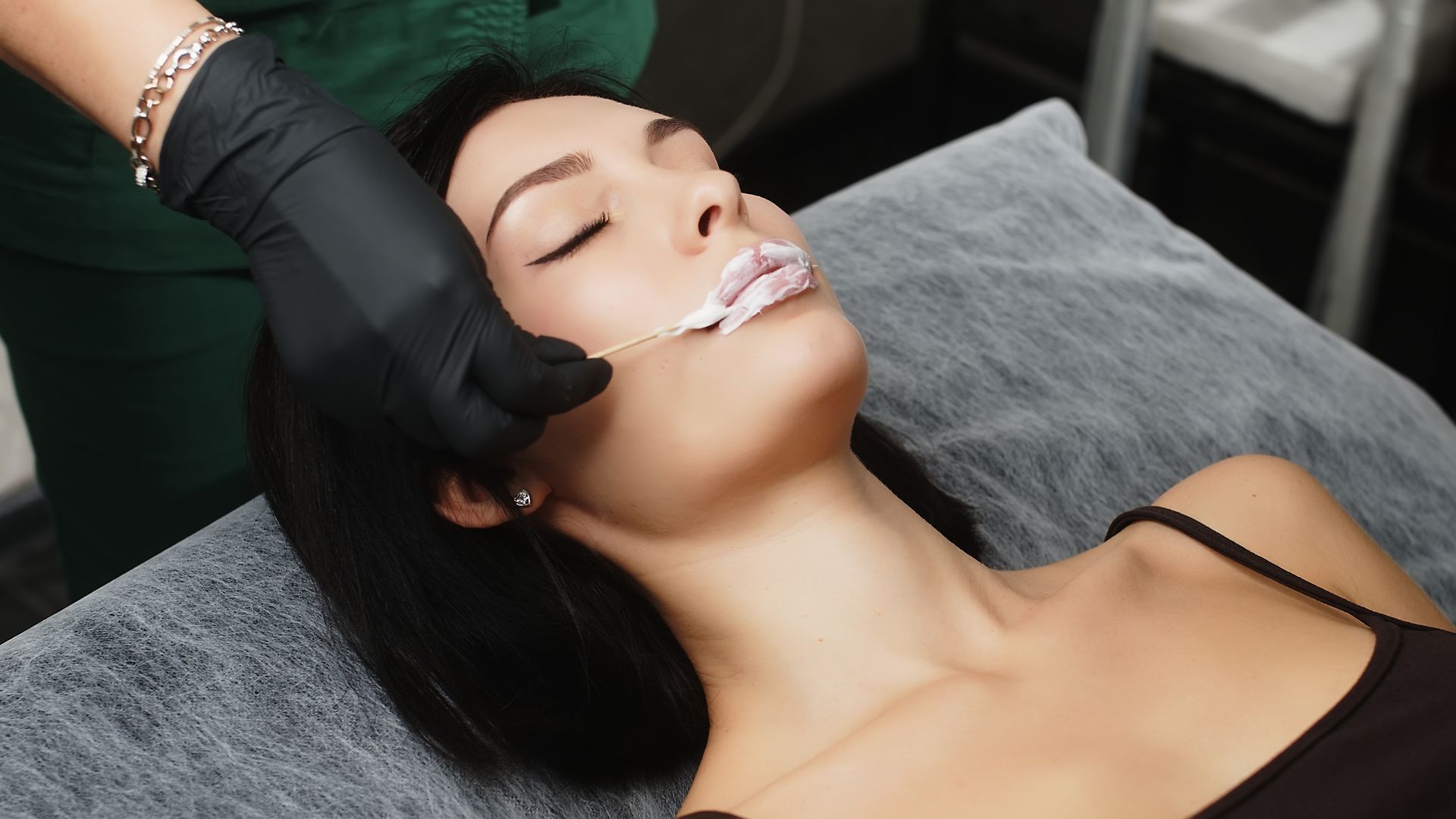 A woman is getting her lips waxed in a beauty salon.