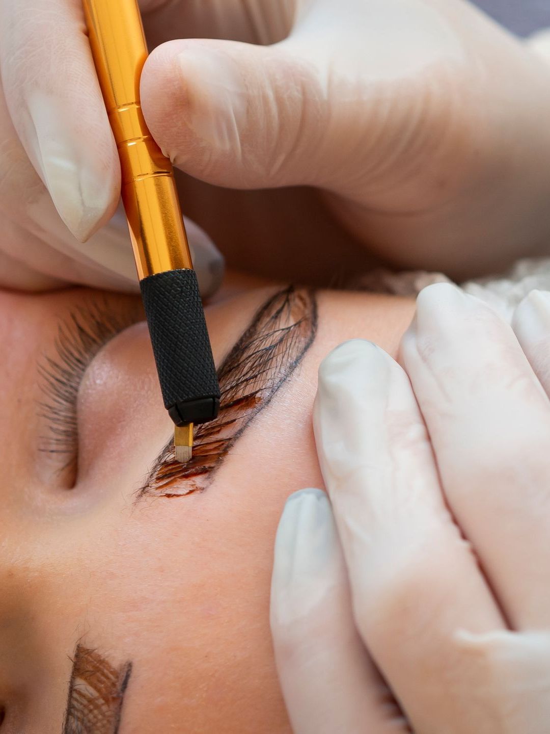 A woman is getting permanent makeup on her eyebrows.