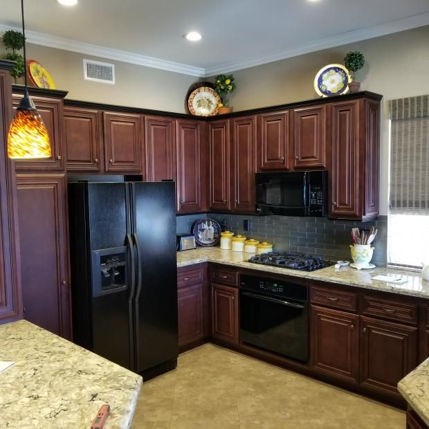 A kitchen with brown cabinets and a black refrigerator