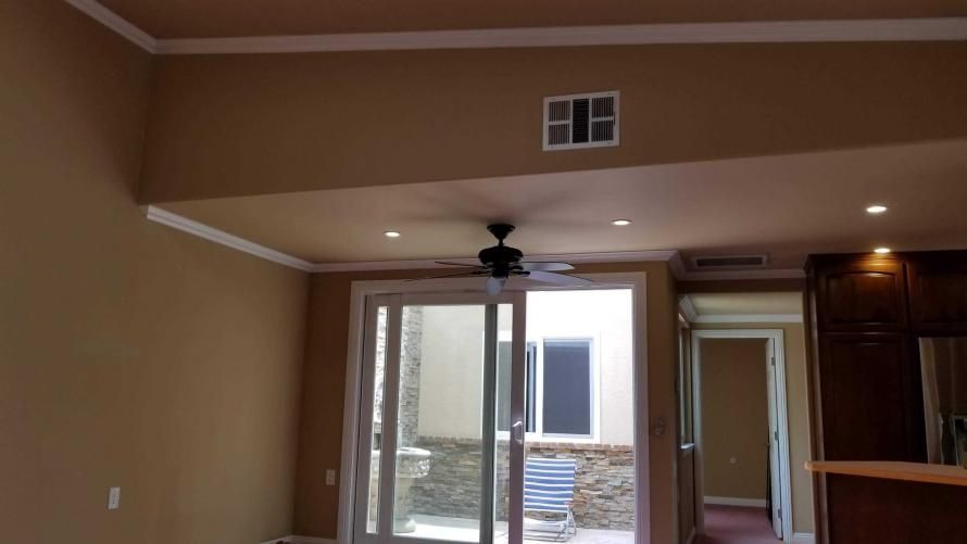 An empty room with a ceiling fan and a sliding glass door