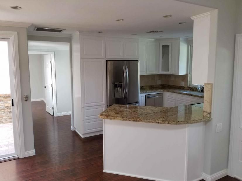 A kitchen with white cabinets and a granite counter top.