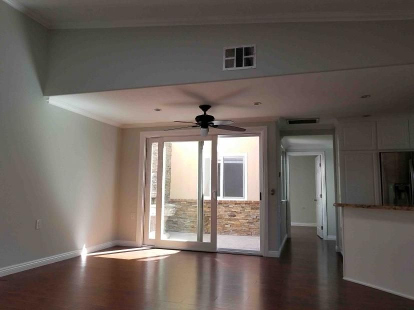 An empty living room with a ceiling fan and sliding glass doors.