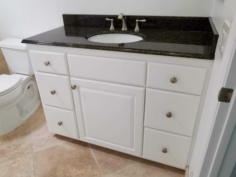 A bathroom with a toilet , sink , and drawers.