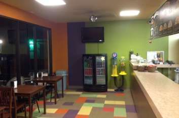 A restaurant with tables and chairs and a refrigerator.