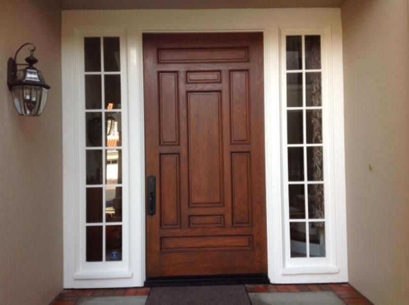 The front door of a house has a light on the wall above it