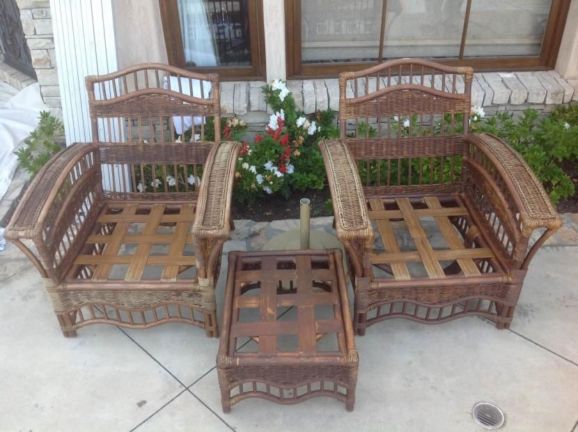 Two wicker chairs and a table are sitting on a patio in front of a building.