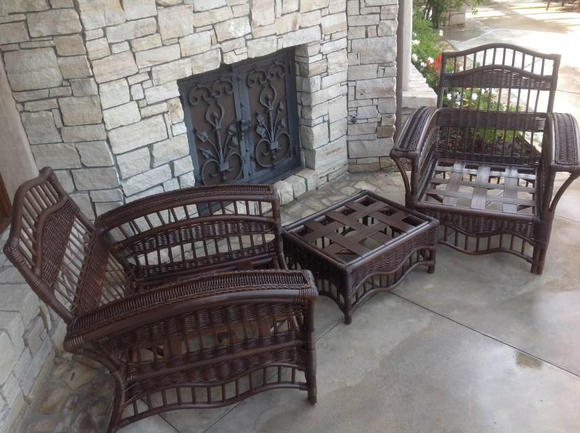 A wicker furniture set is sitting on a porch next to a fireplace.