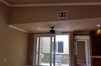 A living room with a ceiling fan and sliding glass doors.