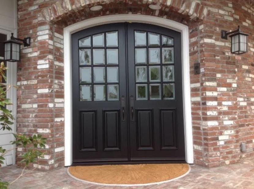 A black door with a brick wall behind it