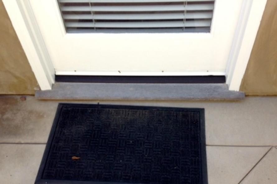 A door with blinds and a black mat in front of it