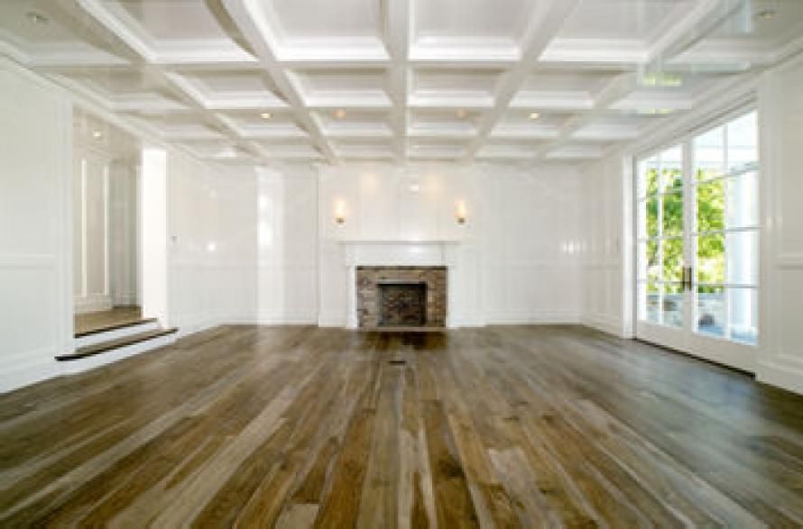 An empty living room with hardwood floors and a fireplace.