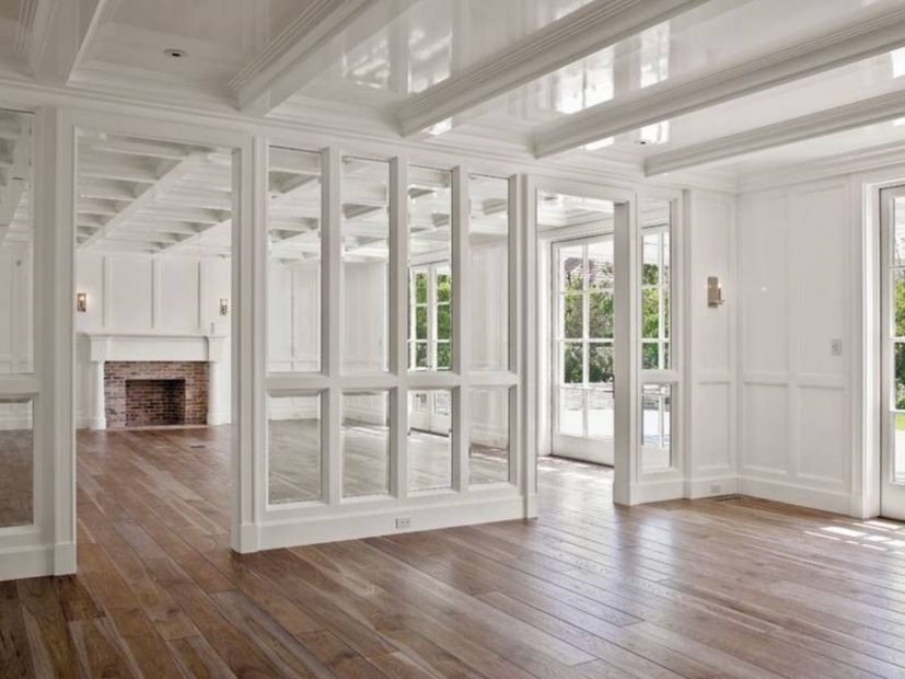 A large empty room with hardwood floors and white walls.