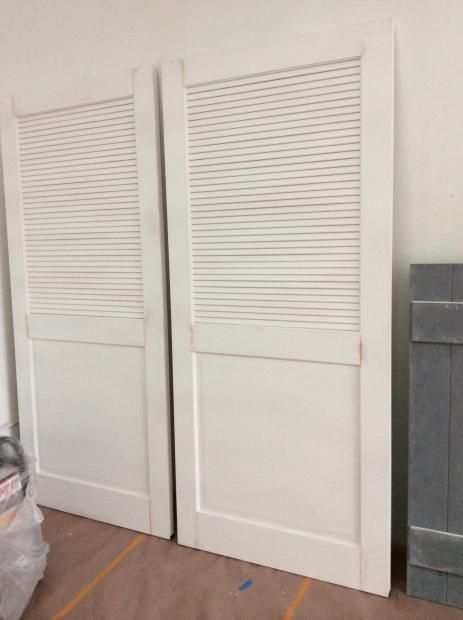 Two white shutters are sitting next to each other in a room.