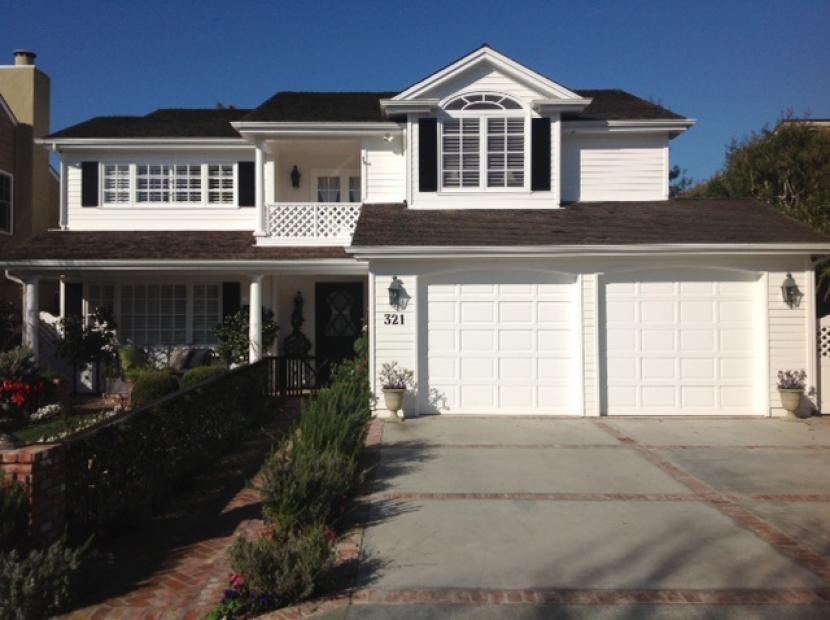 A large white house with two garage doors and a porch