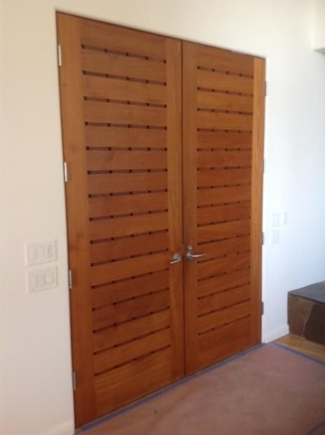 A pair of wooden doors in a room with a white wall