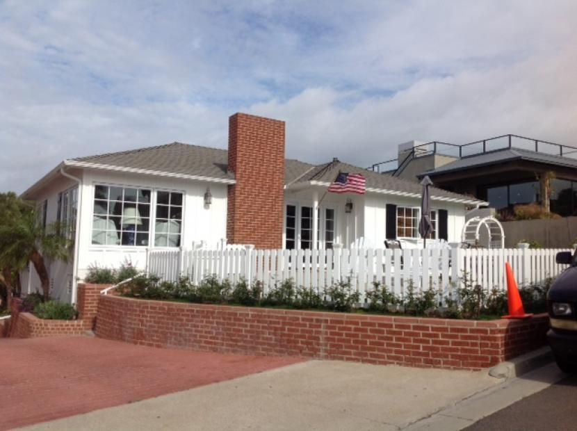 A white house with a brick wall and a white picket fence