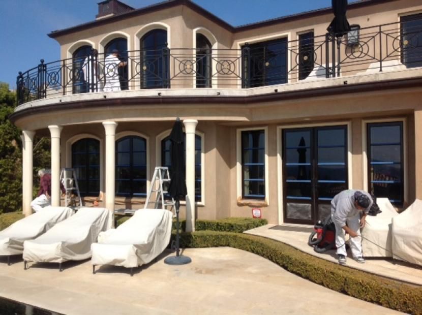 A man is painting the outside of a large house