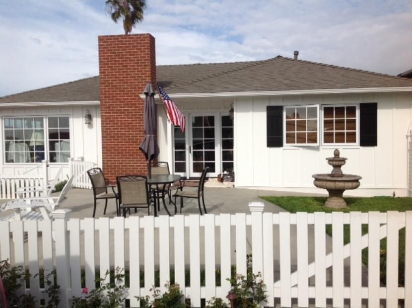 A white house with a brick chimney and a white picket fence