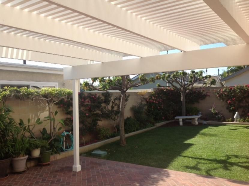 A backyard with a white pergola and a bench