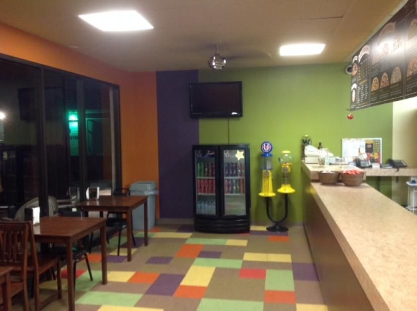 A restaurant with tables and chairs and a refrigerator