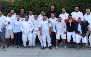 A group of people wearing white shirts and shorts are posing for a picture.