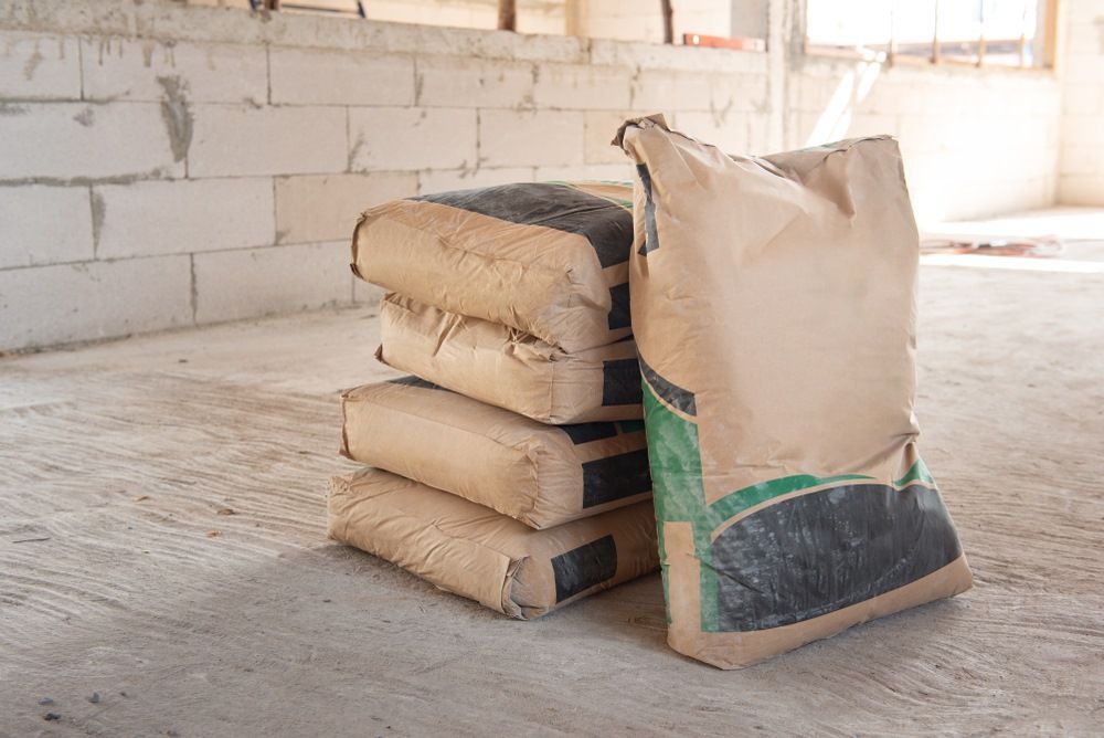 Four Stacked Beige Cement Bags, One Standing — Cessnock Landscaping Supplies In Cessnock, NSW