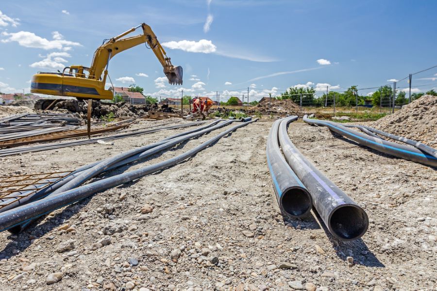 Construction Site with Excavator, Workers, and Black Pipes — Cessnock Landscaping Supplies In Cessnock, NSW
